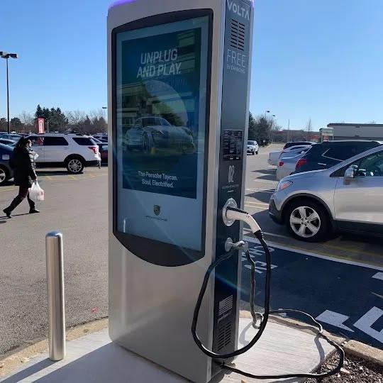 Outdoor EV charging kiosk with a vertical capacitive touch display in a parking lot