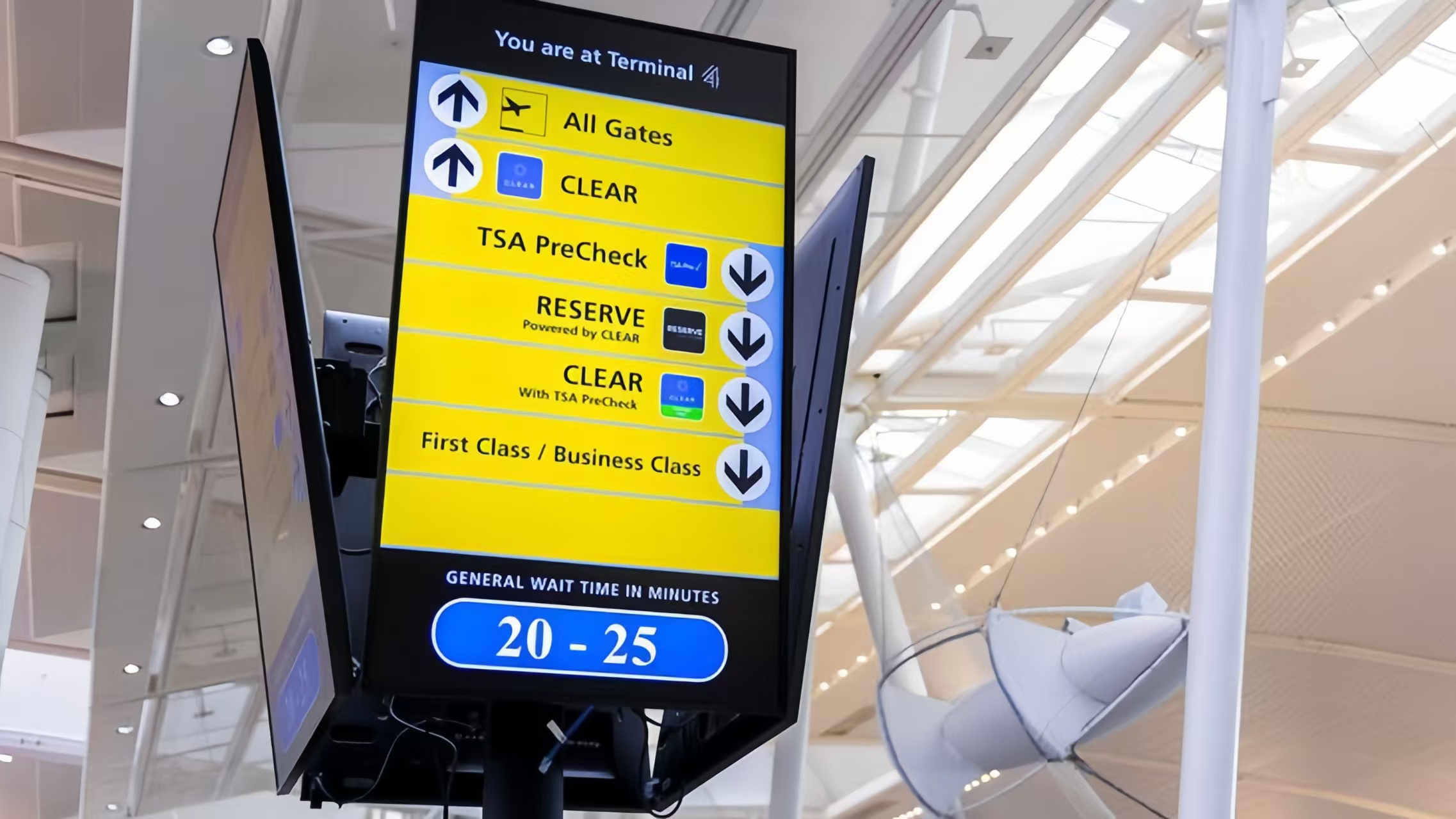 Airport Terminal 4 digital wayfinding pillar showing gate directions and general wait time