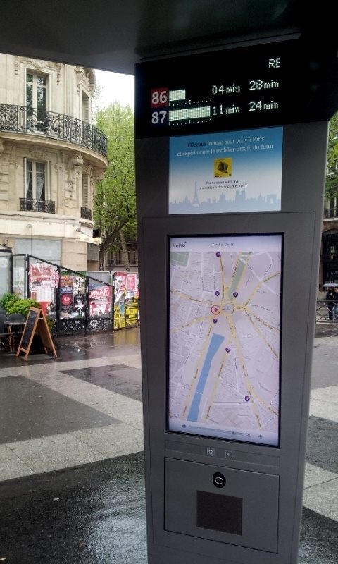 Outdoor transit information kiosk with a city map on a rainy urban street