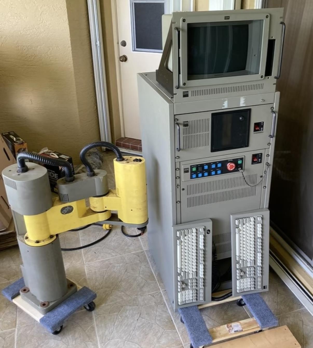 Industrial rack-mounted control computer and robotic arm on a factory floor