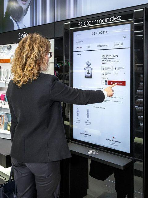 Shopper using a large retail capacitive touchscreen kiosk to browse and order products