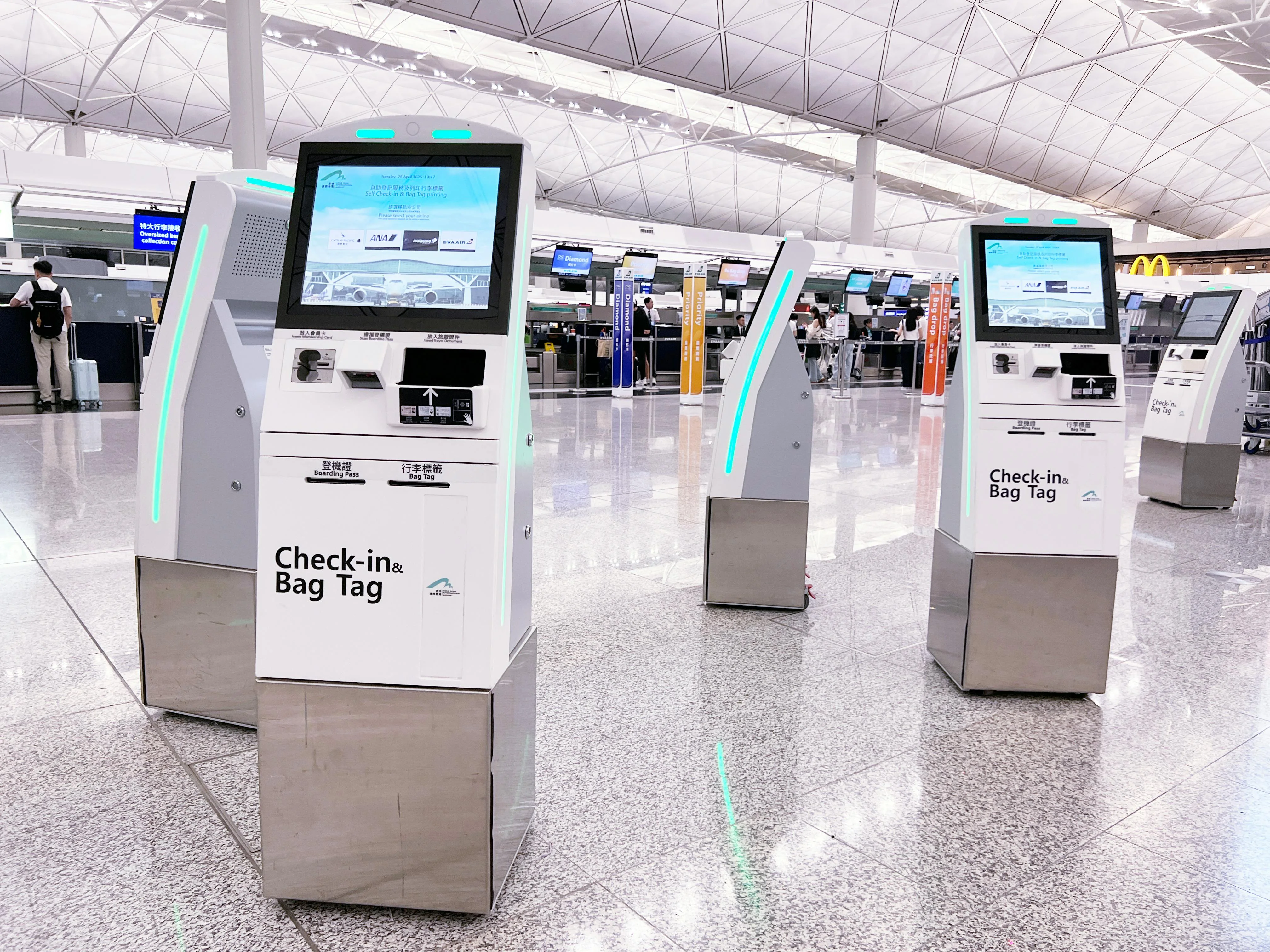 Travelers using touchscreen wayfinding and ticketing interfaces in a public concourse